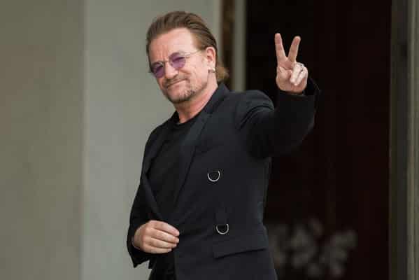 Celebrity weird facts, strange true stories about celebs, celeb facts that will make you rethink them forever, bono with a peace sign black suit