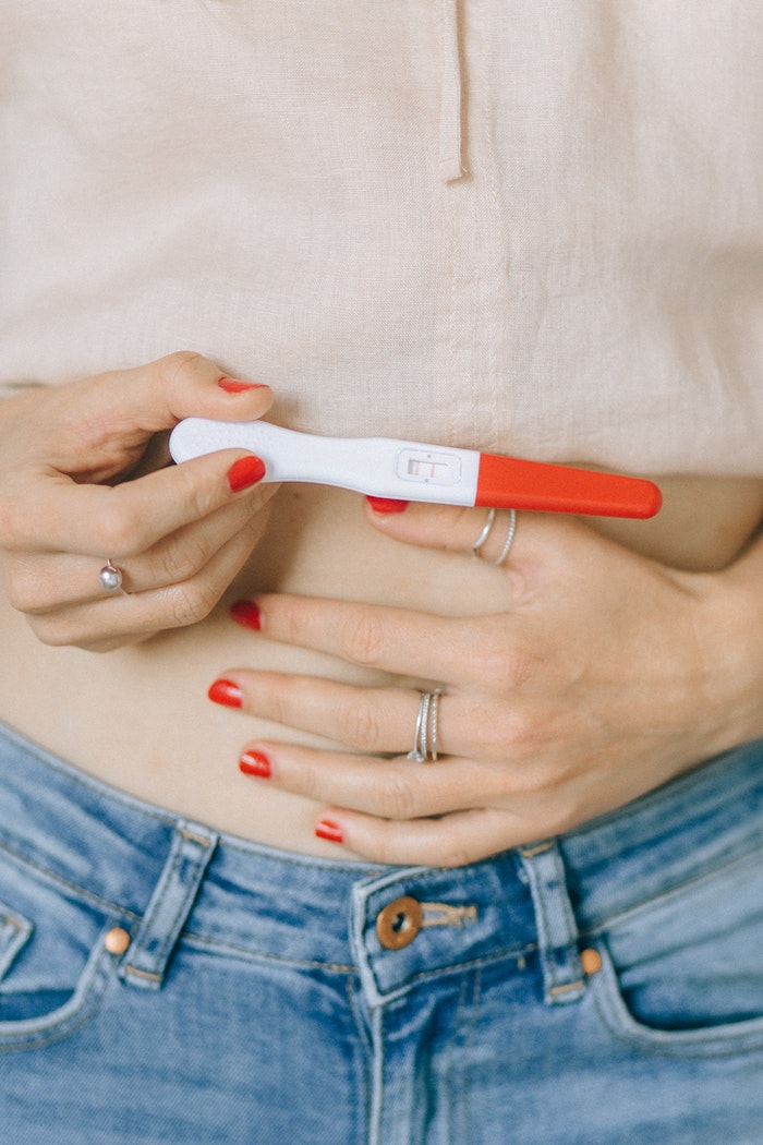 Woman Holding Her Belly and Pregnancy Test Kit