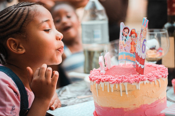Happy little ethnic child blowing out candles during birthday celebration