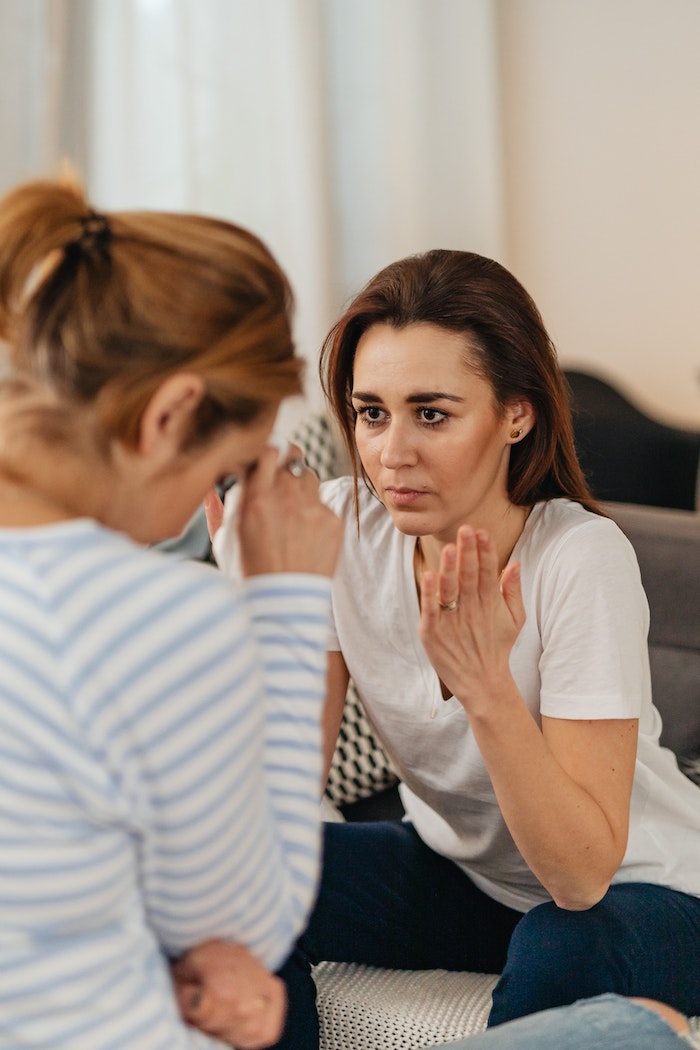 Photo of a Woman in a White Shirt Looking at Another Woman