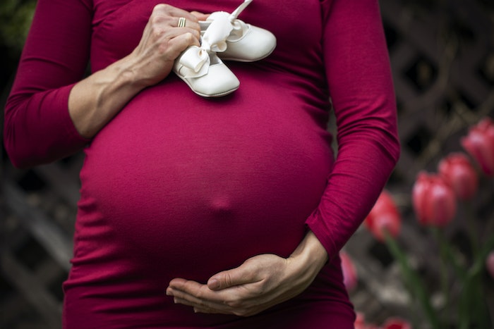 Pregnant Woman Holding baby's shoes