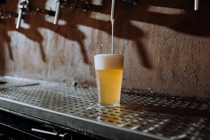 Beer Pouring Into Clear Drinking Glass on Metal Surface