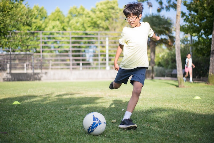 Boy in White T-shirt and Black Shorts Playing Soccer