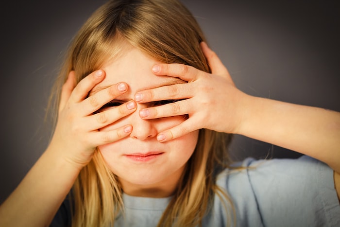 woman in white shirt covering her face with her hand