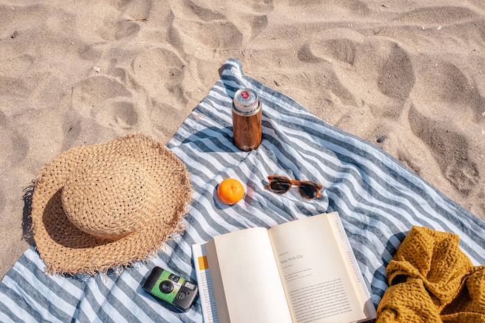 brown glass bottle beside white book on blue and white textile